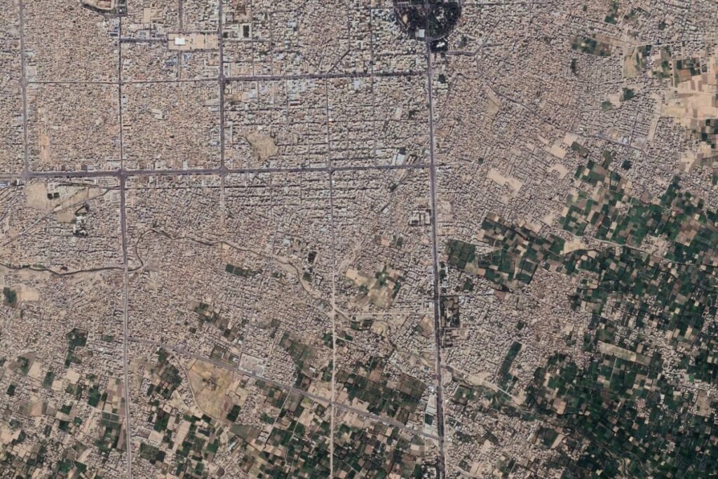 Aerial view of Herat, Afghanistan, highlighting the dense urban fabric intersected by roads and surrounded by agricultural fields