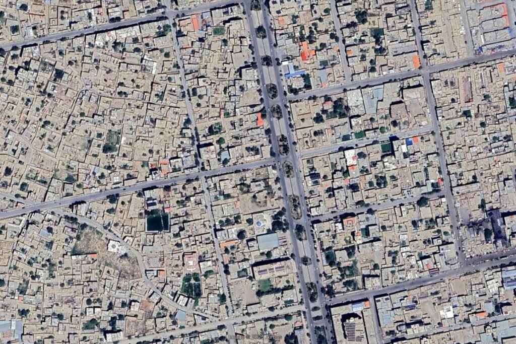 Aerial view of Mazar-e-Sharif, Afghanistan, showing a mix of formal street grids and densely packed informal settlements with minimal open spaces.