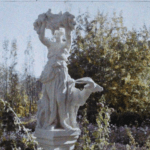 A white marble statue of a woman with a goat, surrounded by vibrant garden foliage, representing the elegance of 1920s Afghanistan
