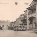 Vintage photograph showing vehicles and a colonial-era building in Laghman Province, Afghanistan.