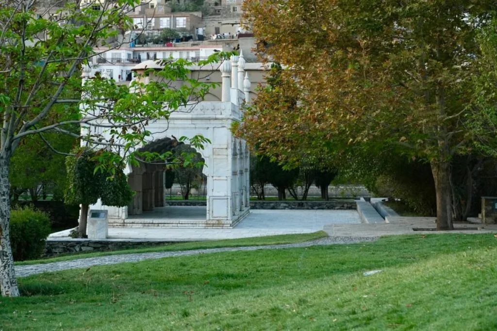 Babur's Mosque in Bagh-e Babur, a marble structure with an arched entrance, surrounded by lush greenery and pathways