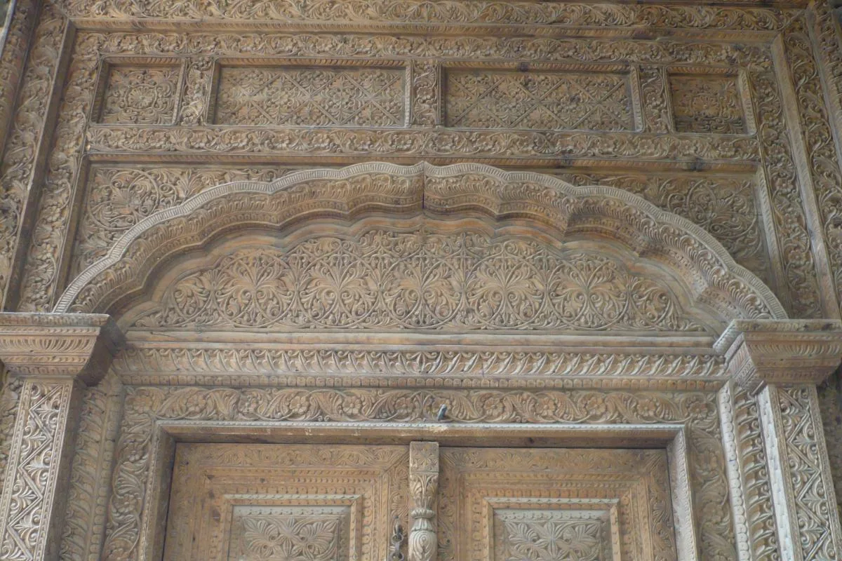 Intricate wooden carvings on a traditional doorway in Kabul, showcasing detailed floral and geometric designs.