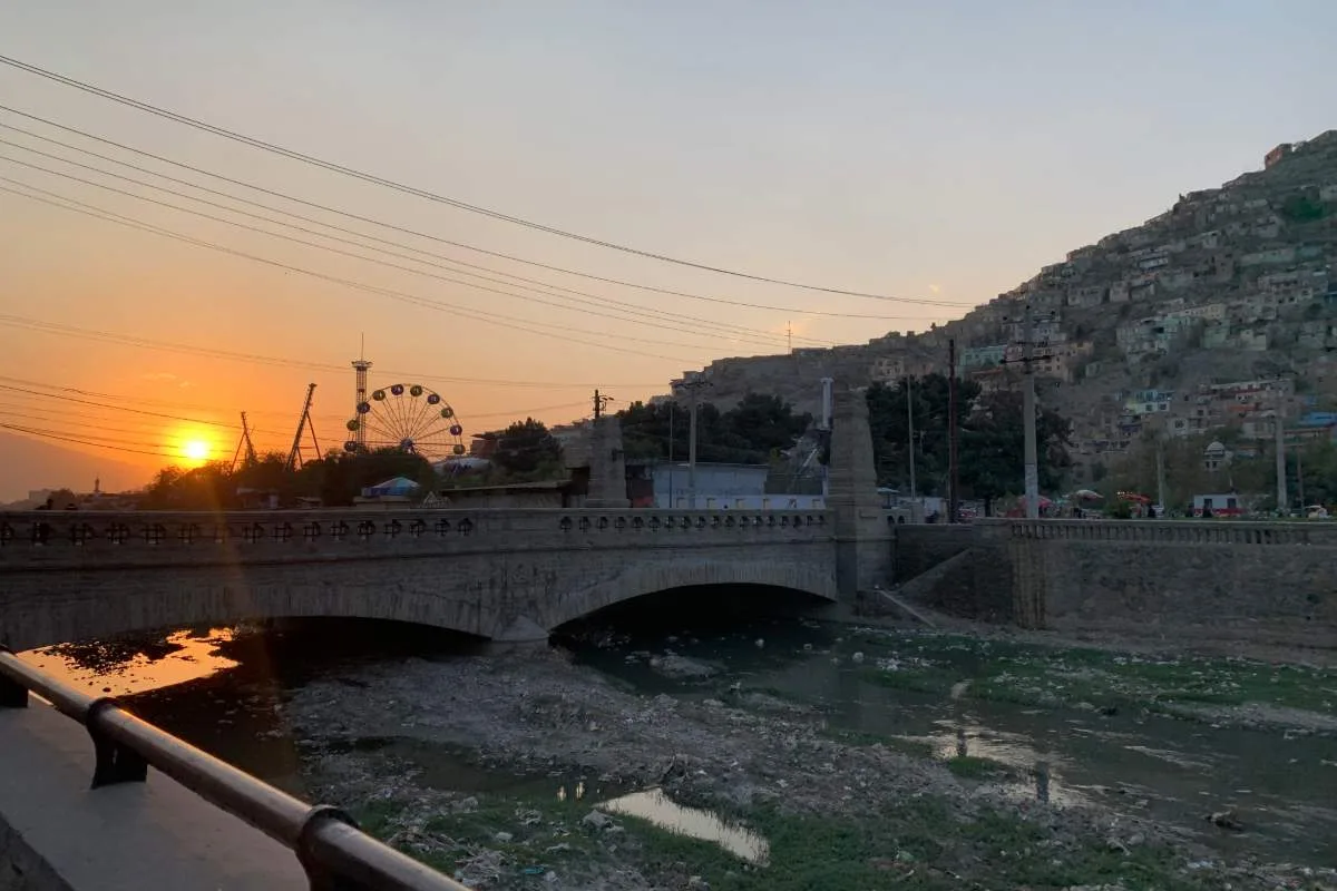 Pule Artal bridge in Kabul offers a picturesque scene, especially during sunset. The bridge spans a small river, with the Ferris wheel and bustling city life creating a unique urban backdrop. The hillside homes and the soft golden glow of the setting sun make this spot an ideal location for photography and a glimpse into Kabul's dynamic landscape.
